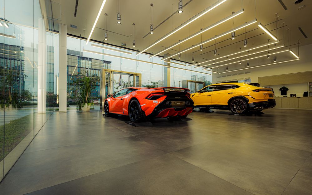 Orange and yellow sports cars displayed in a glass-walled showroom