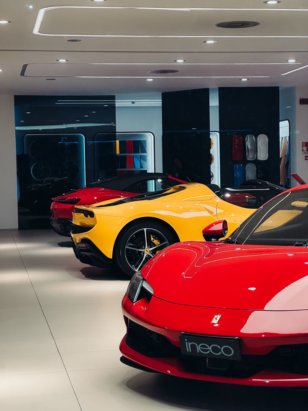 Red and yellow sports cars on display in a dealership showroom