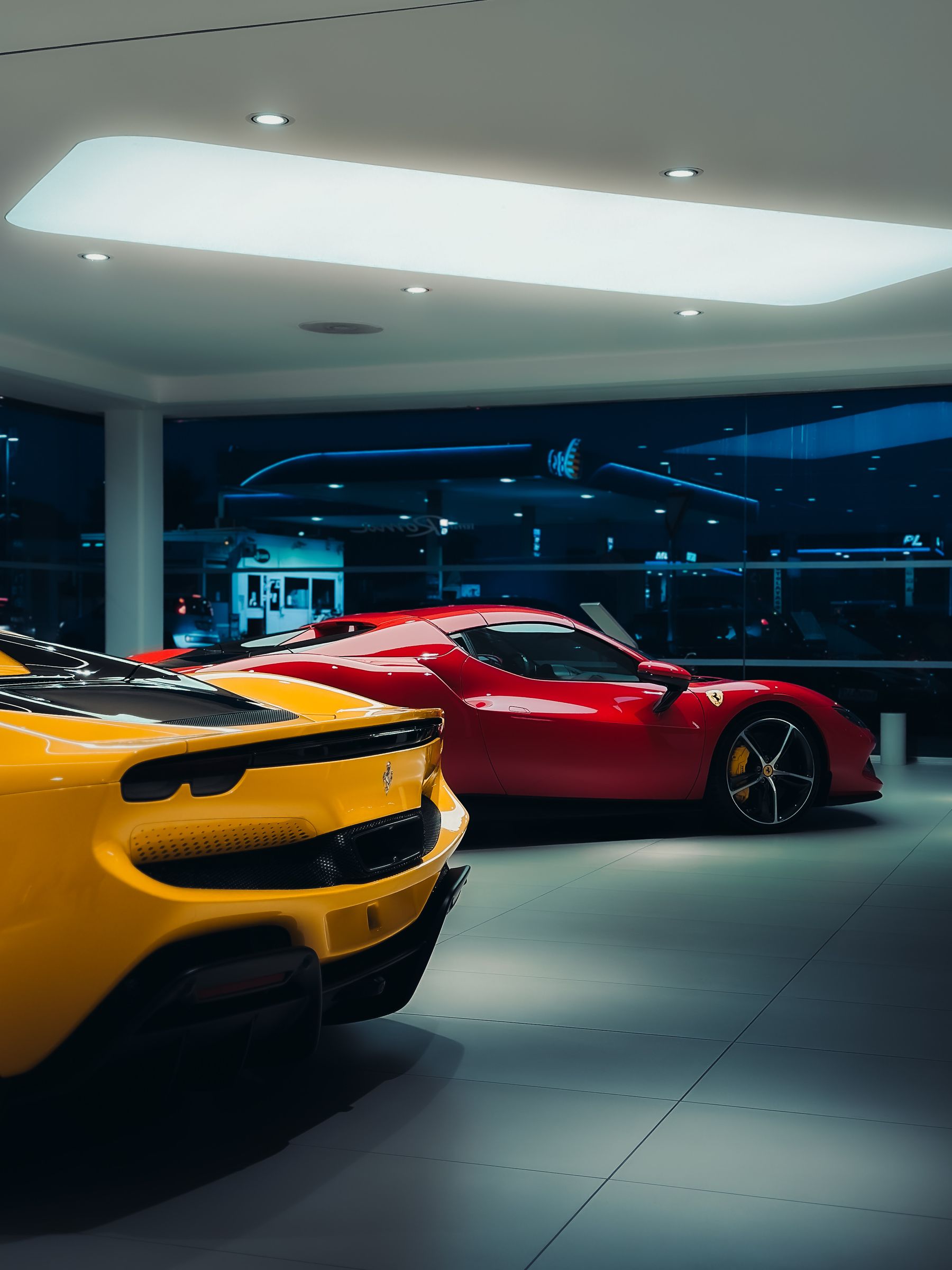 Yellow and red sports cars displayed under dramatic lighting in a modern showroom