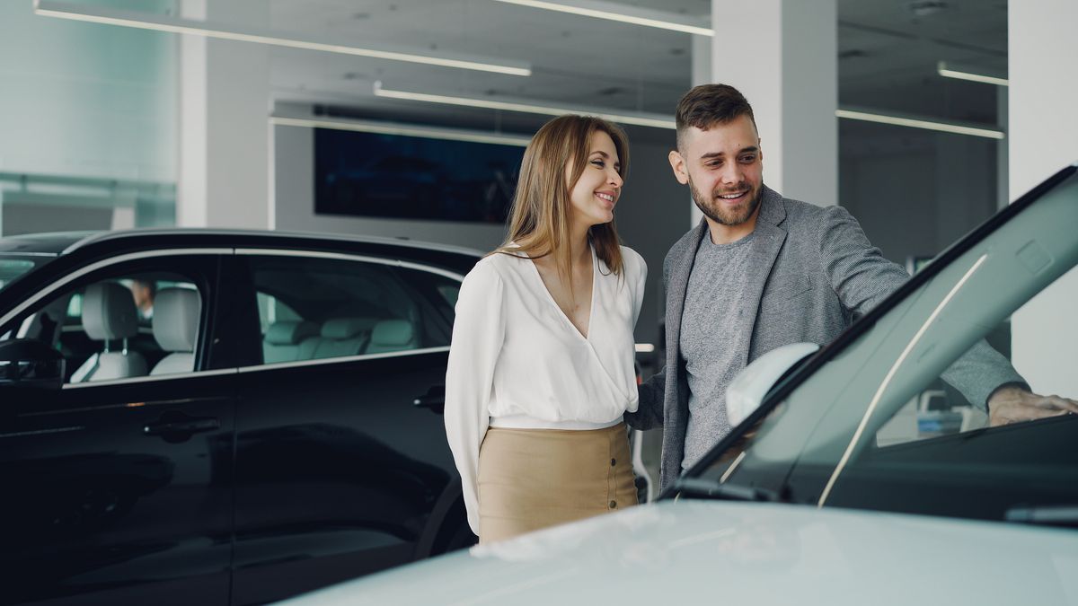 A salesperson showing a couple a car on the showroom floor
