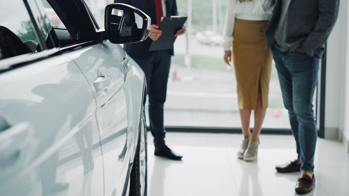 A sales consultant walking a customer through the showroom beside a car