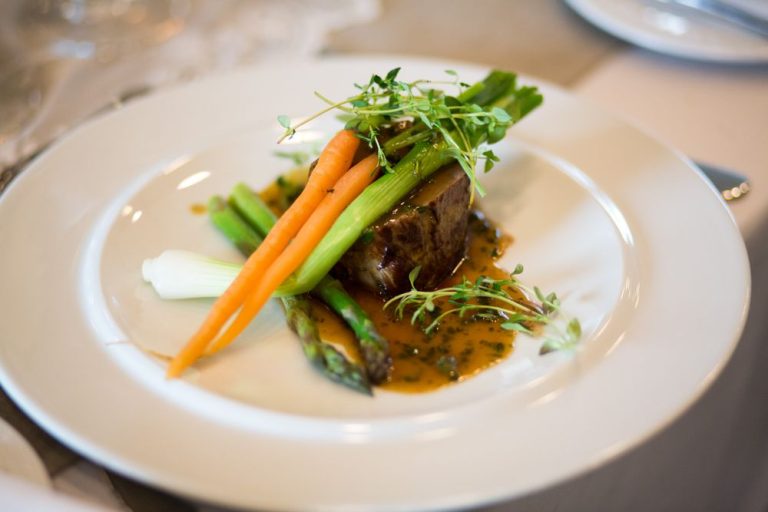A plated main course with carrots and green garnish on a white plate
