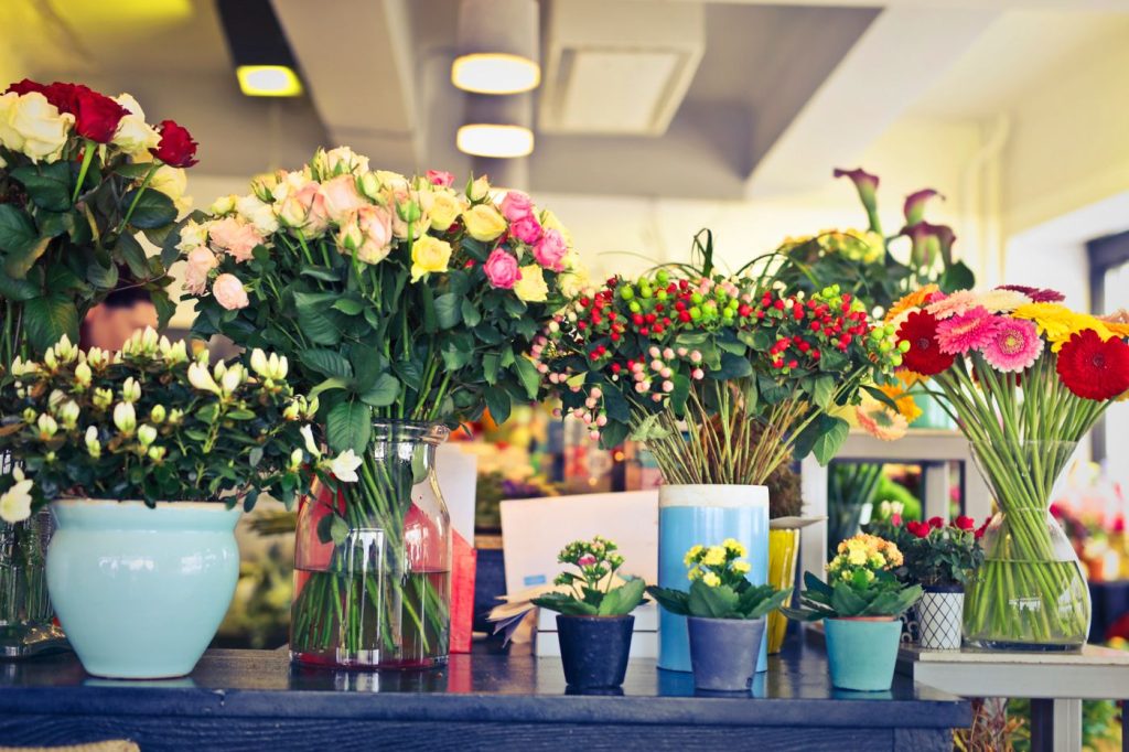A florist's shop counter crowded with colourful cut flowers in vases