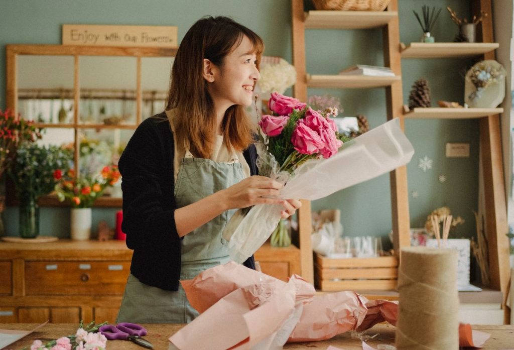 A florist arranging a bouquet at her workbench in a small flower shop