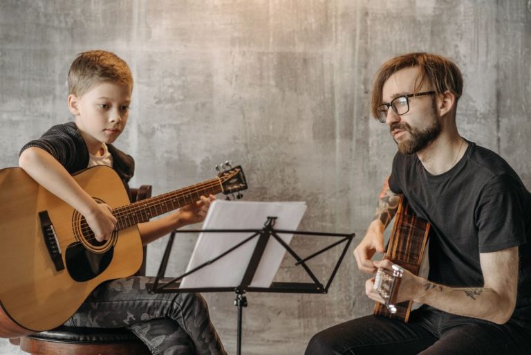 A guitar teacher and a young student playing together