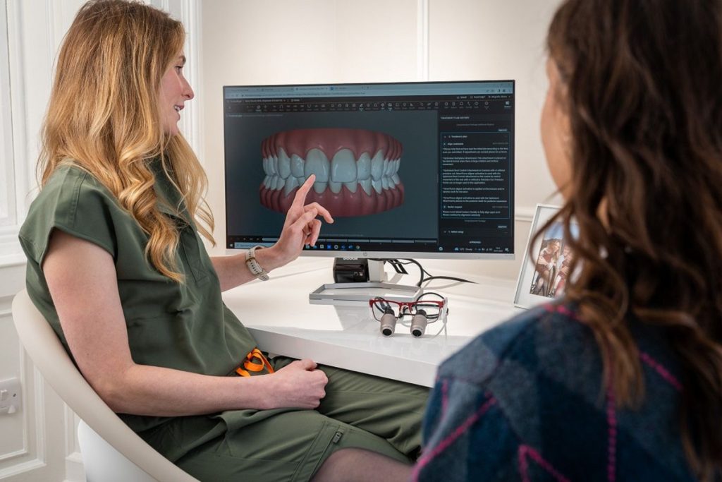 A dentist showing a patient a scan of her teeth on a monitor