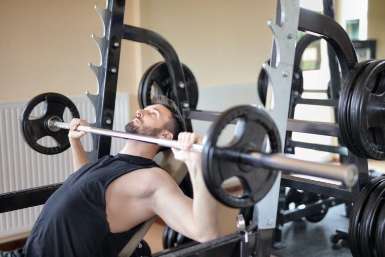 A man bench pressing a barbell in a power rack