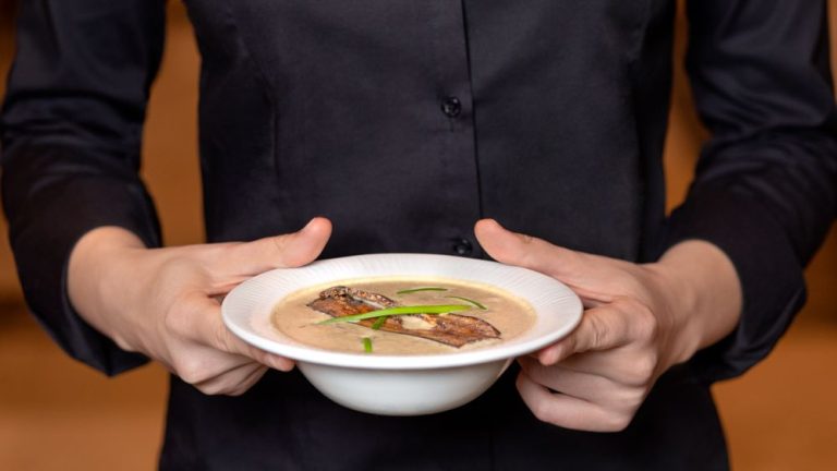 Hands holding a bowl of hot soup