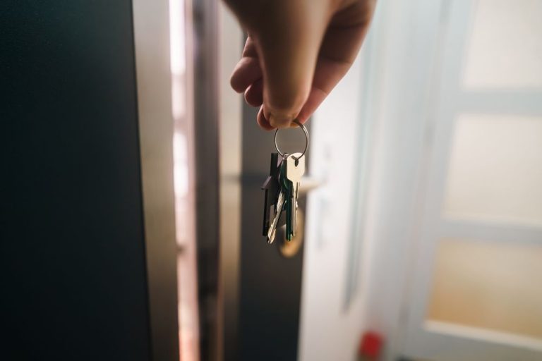 A hand turning a key in an open front door
