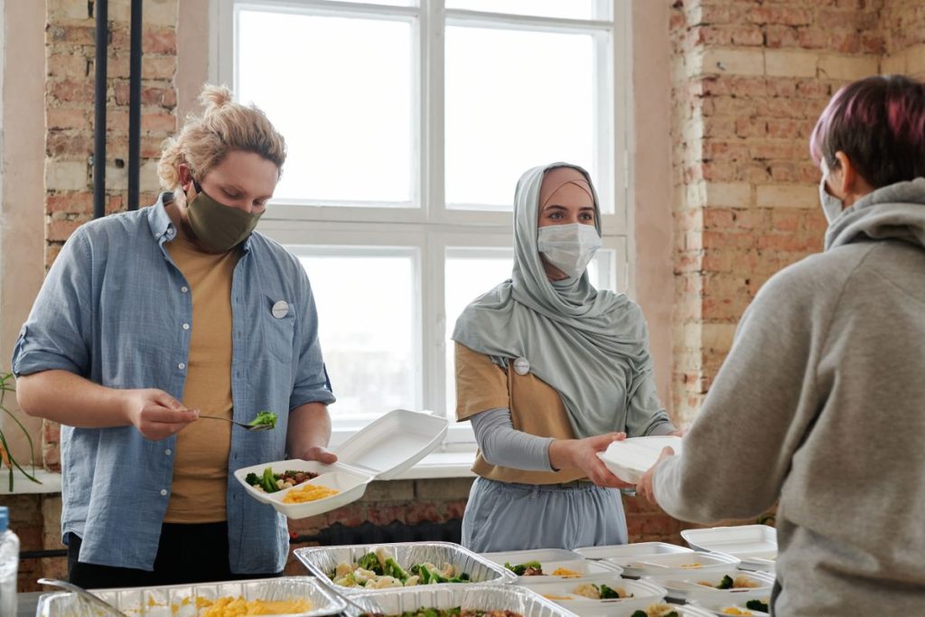 Volunteers serving meals in takeaway containers