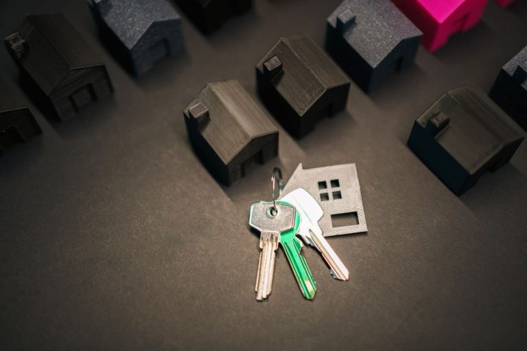 A set of house keys beside small model houses