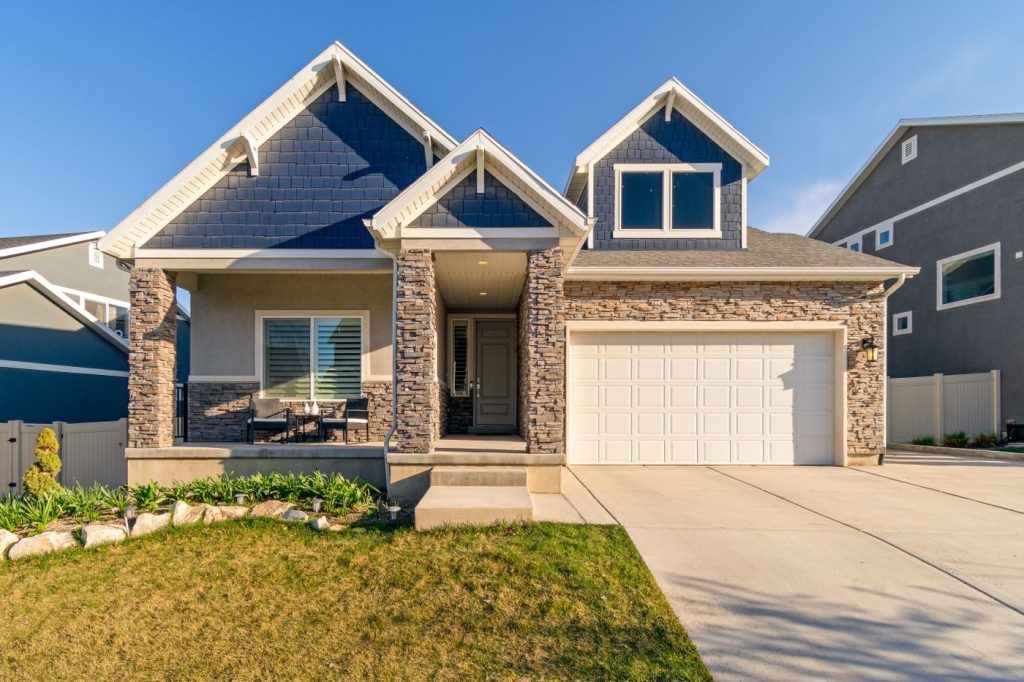A two-storey family house with blue siding and a garage on a sunny day