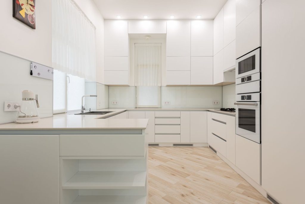 A modern white kitchen with an island and built-in appliances
