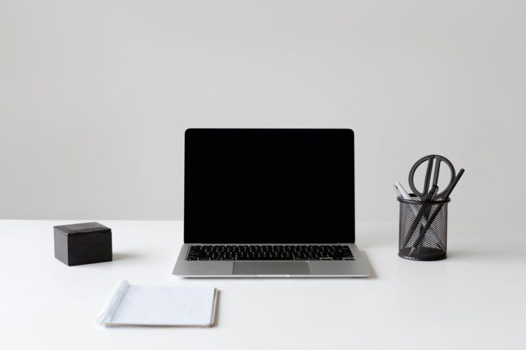 A laptop and a pen holder on a clean white desk