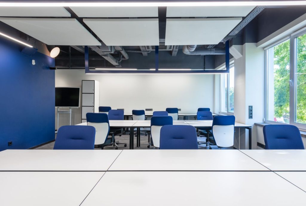 A bright open-plan office with white desks and blue chairs