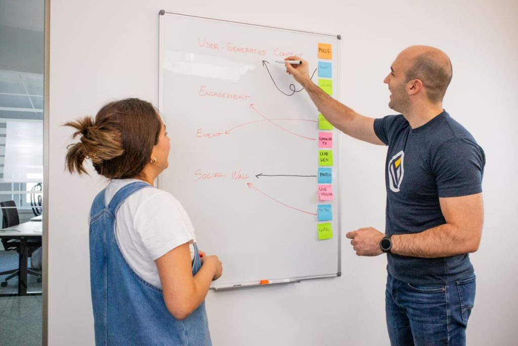 Two colleagues planning at a whiteboard covered in notes