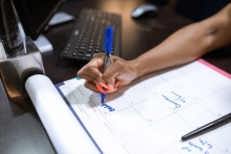 A person marking dates on a planner at a desk