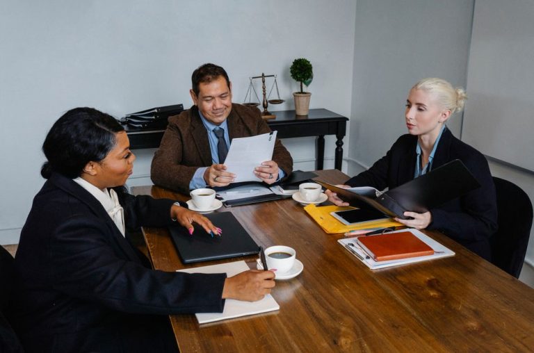 Three professionals reviewing documents around a table