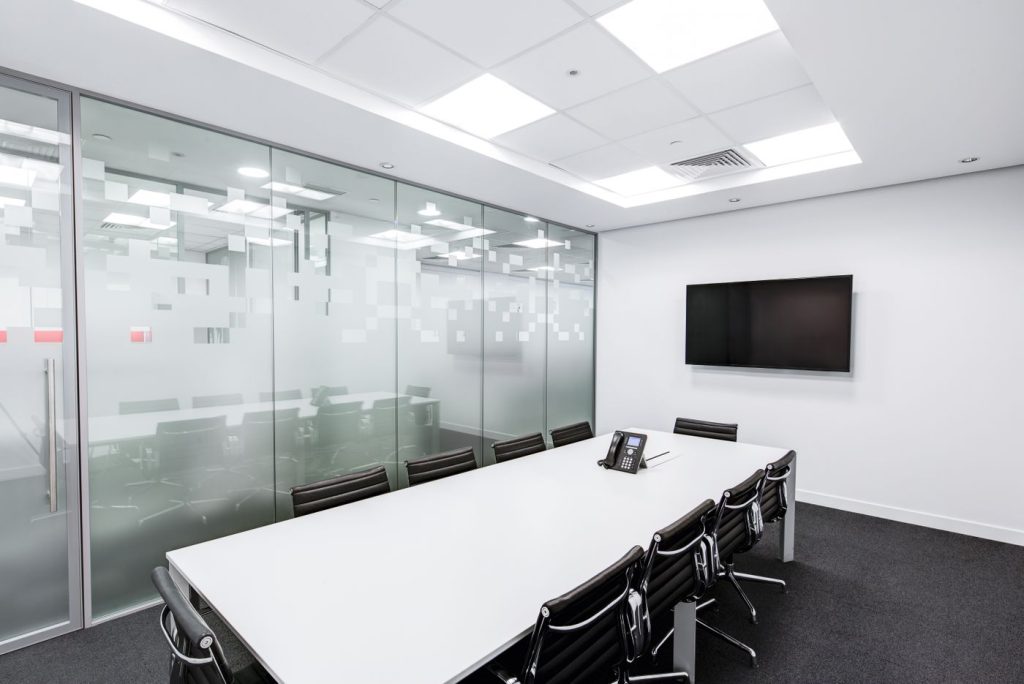 A bright glass-walled meeting room with a long white table