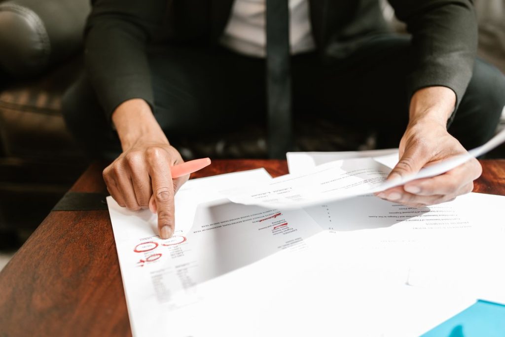 Hands reviewing and marking financial documents on a desk