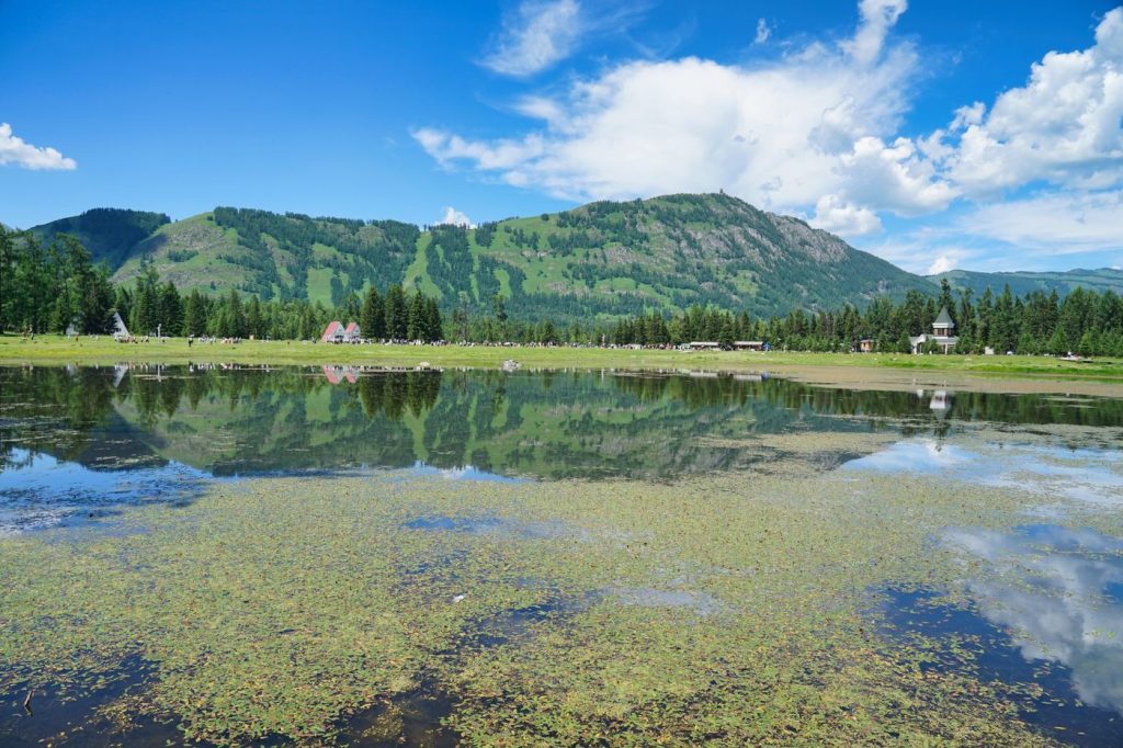 A mountain lake reflecting a blue sky and green hills