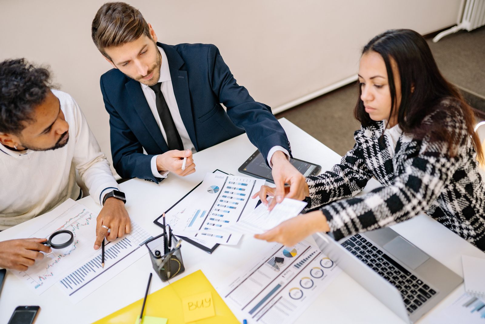 Three consultants reviewing a client's business plan and financial charts together at a desk