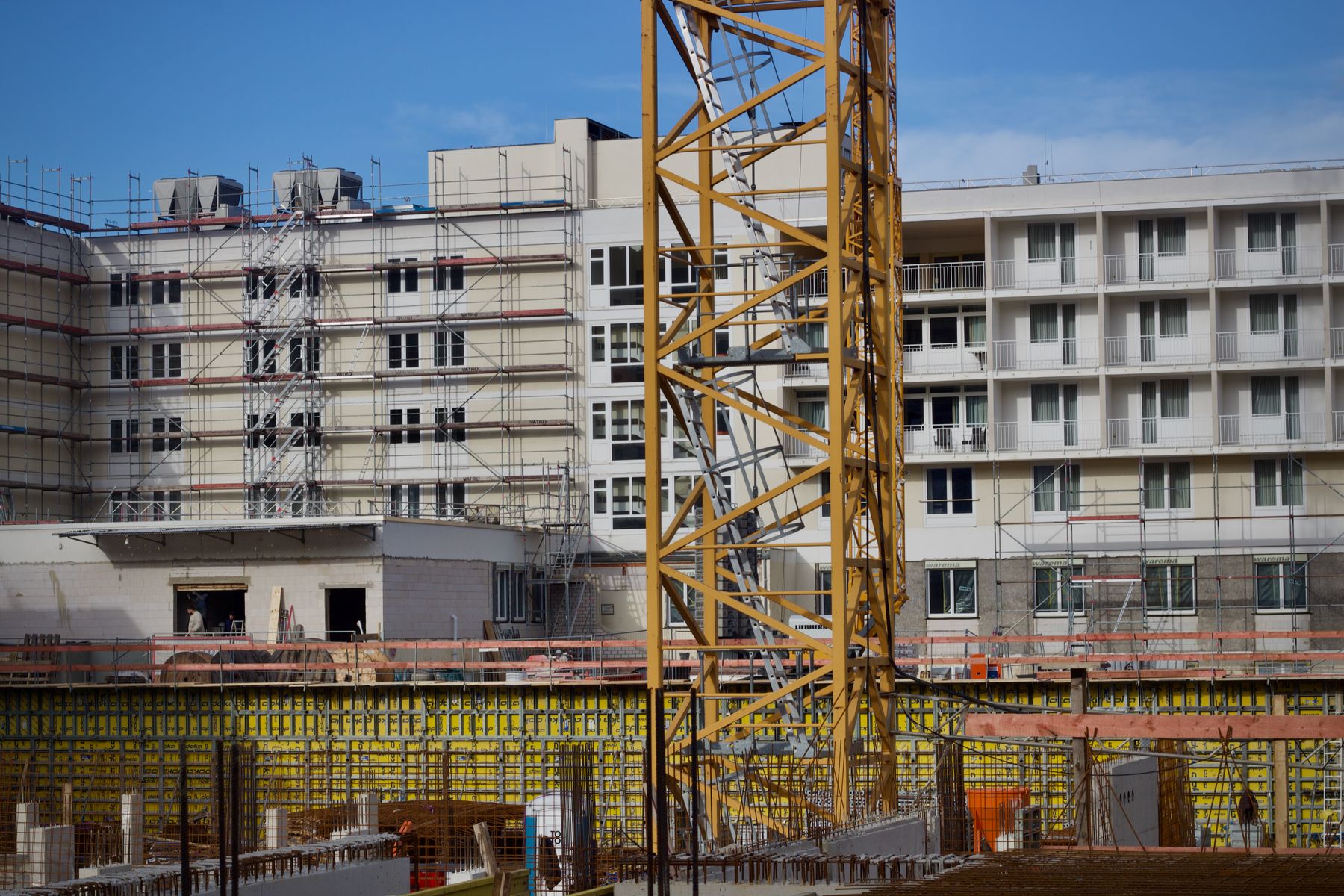 A residential building under construction with a yellow tower crane on a sunny day