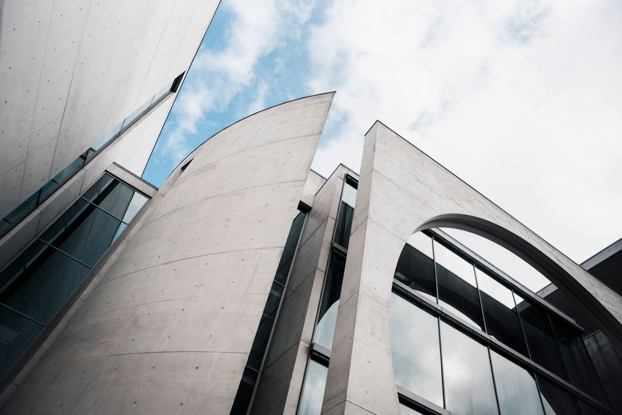 A curved concrete civic building with a large glazed arch