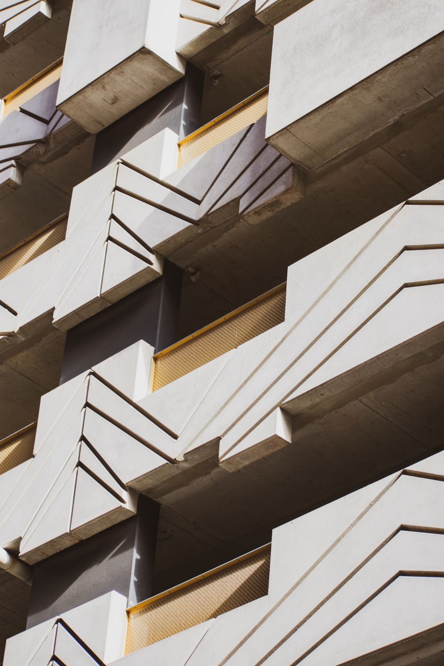 A concrete facade with deep angular balconies