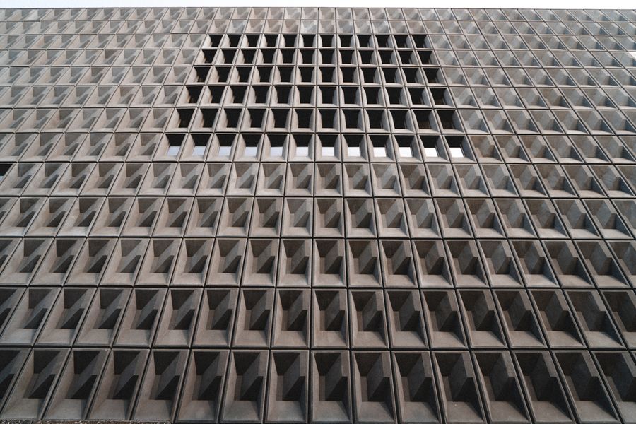 A large concrete grid facade with a glazed section