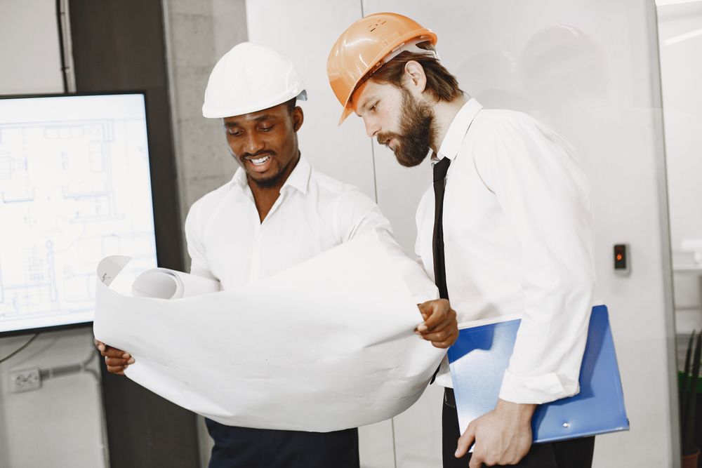 Two colleagues in hard hats reading site plans together