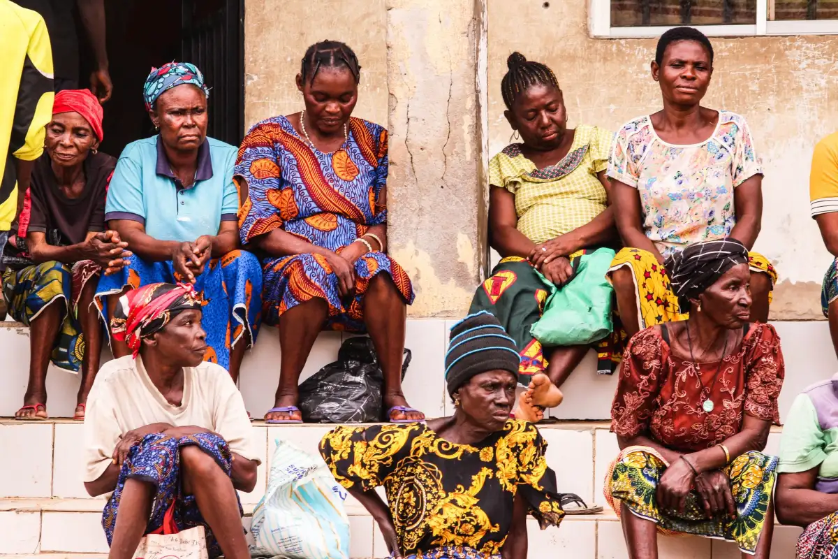 A group of women in colourful dresses sitting together on the steps of a building