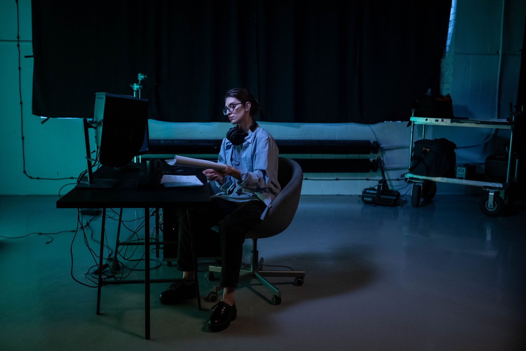 A designer working at a desk in a dark studio lit with teal light