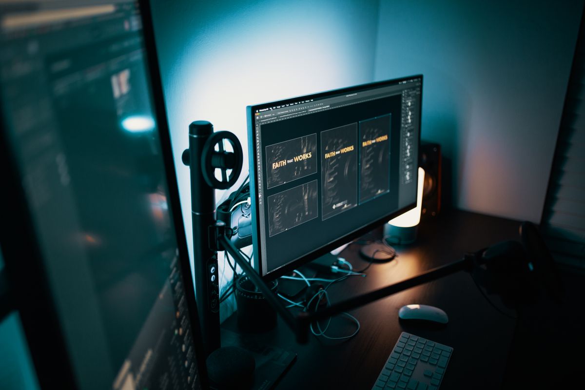 A monitor showing design software on a dark desk lit with teal light