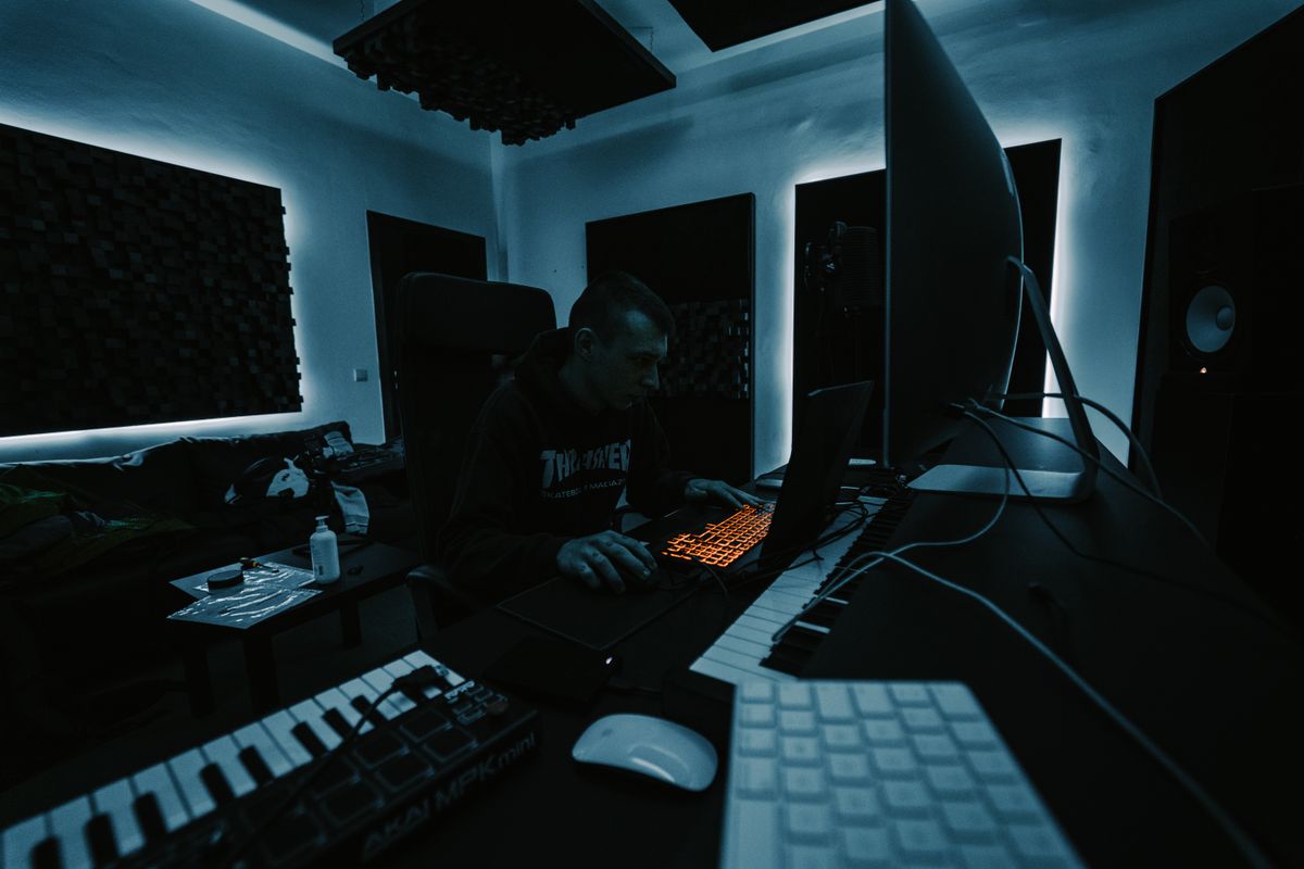 A dark music and video studio with keyboard, monitors and lighting