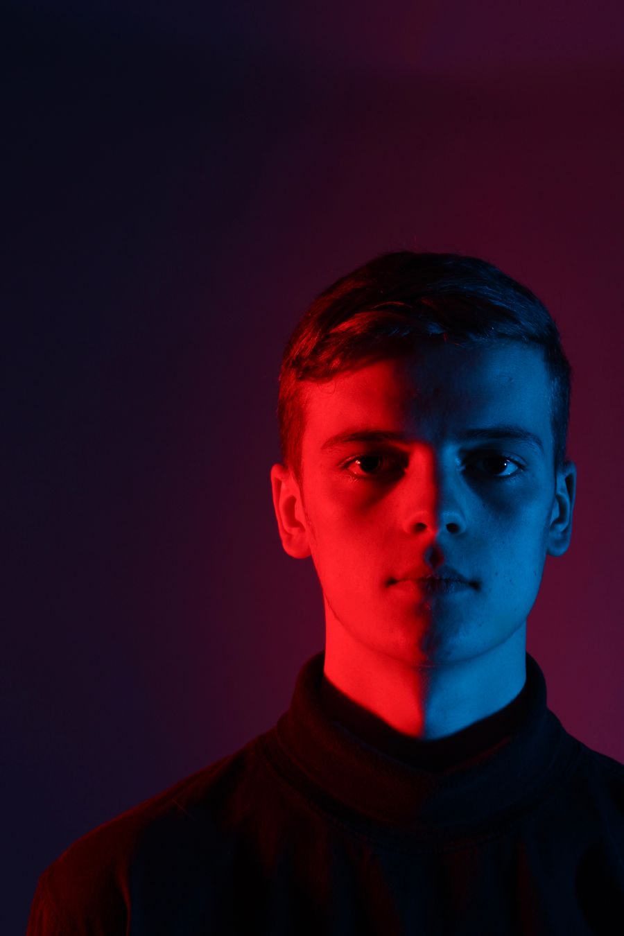 Portrait of a young man lit in red and blue