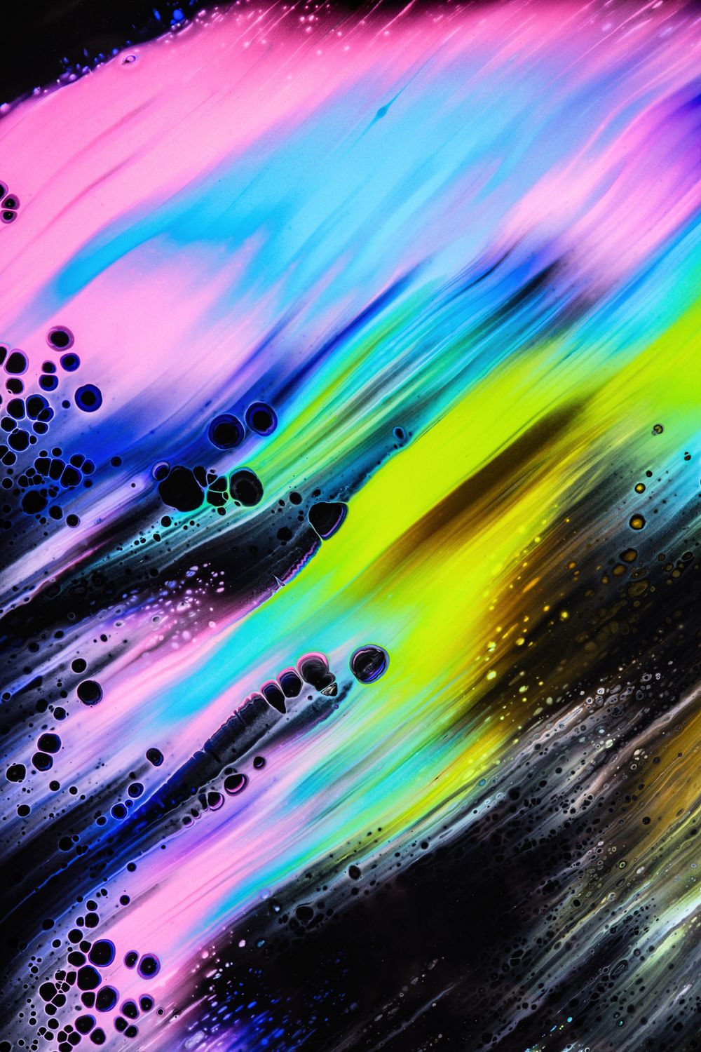 Swirling ink in pink, cyan and lime against black