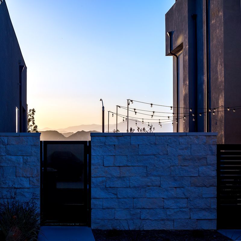 A stone wall and gate at sunset in a modern development