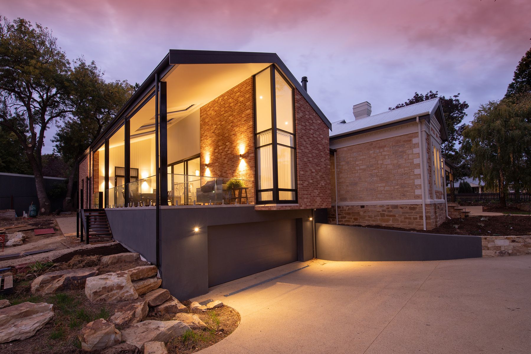 A modern glass-fronted house lit warmly at dusk