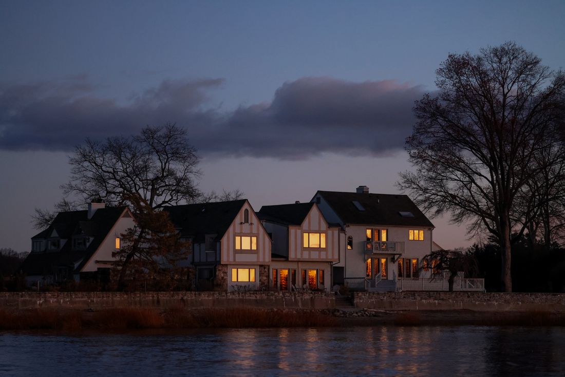 Row of pitched-roof houses beside a lake at dusk
