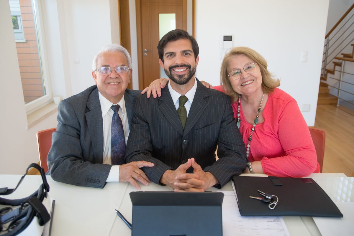 An estate agent sitting with an older couple at a table going through paperwork