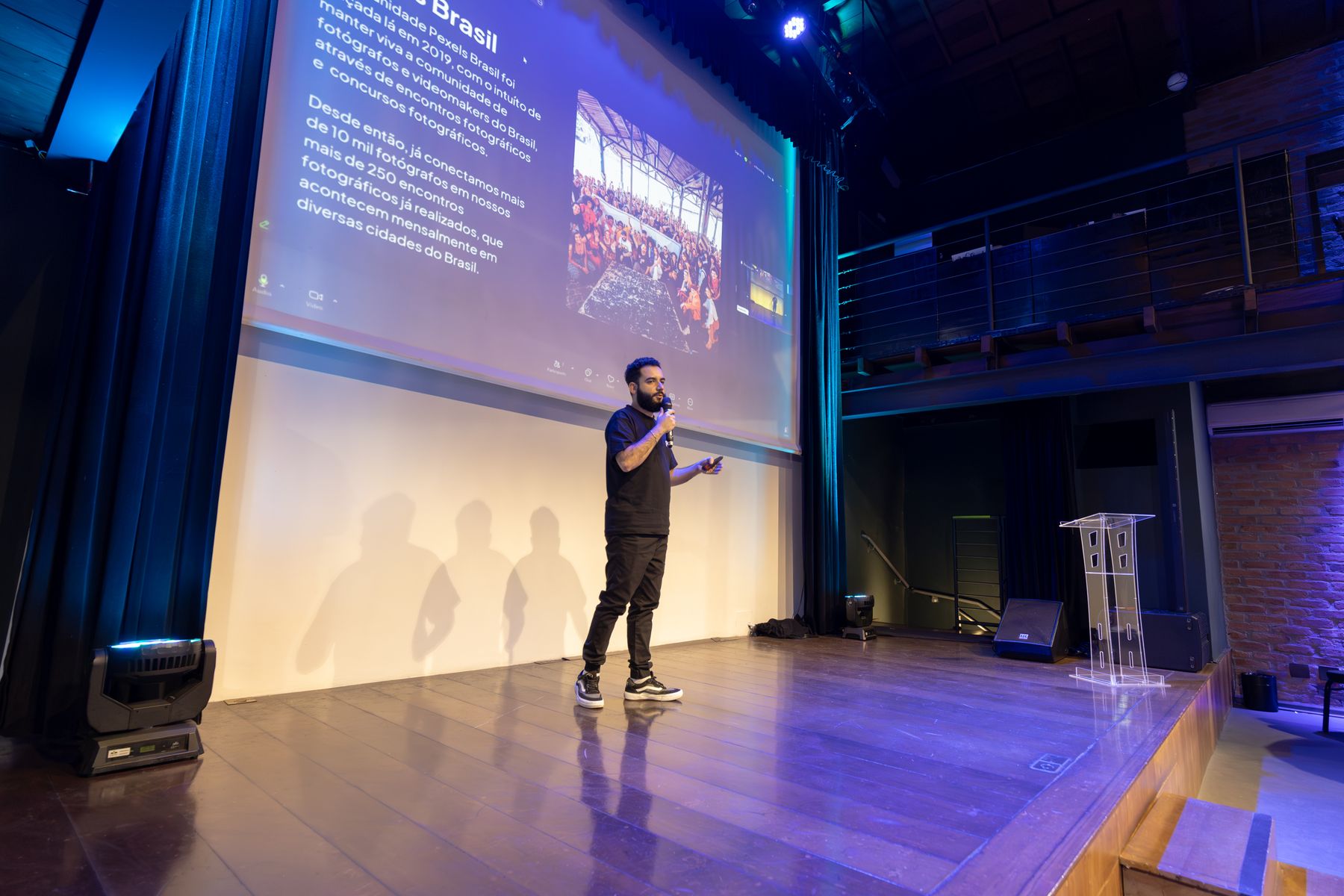 A speaker presenting on a dramatically lit conference stage