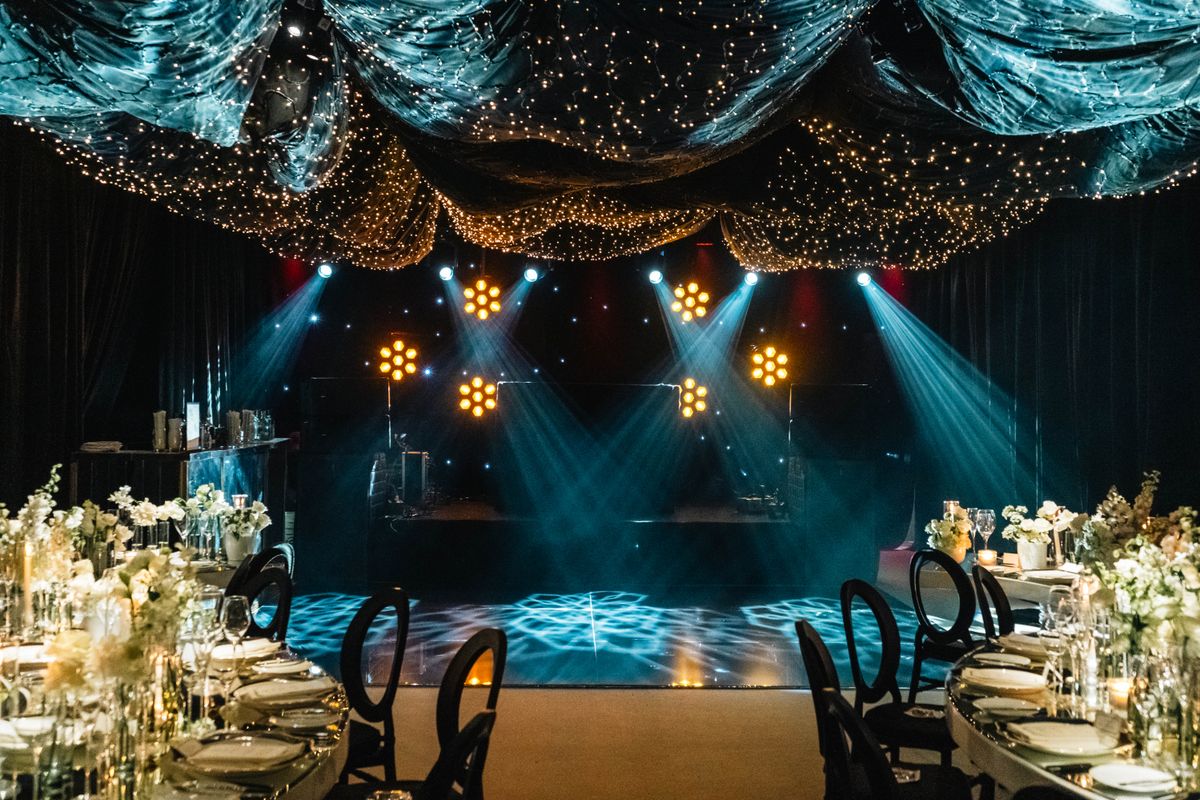 An elegant event venue set for a banquet with ambient stage lighting