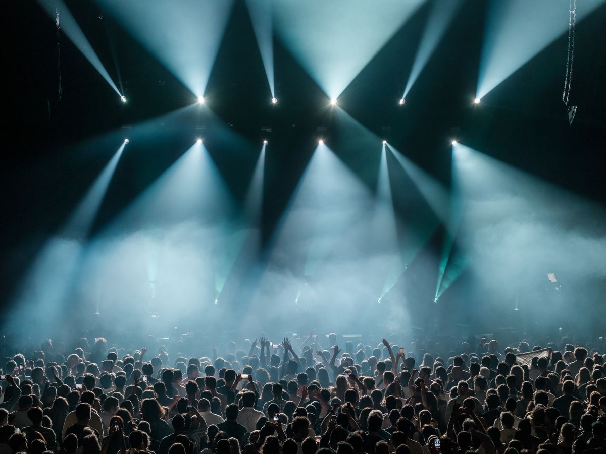 A crowd under dramatic stage lights at a live concert