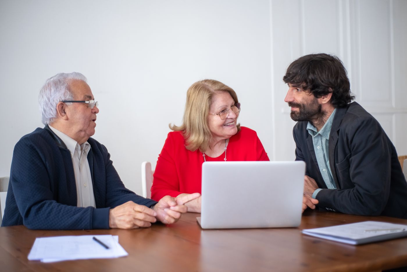 Two older clients and an adviser talking around a laptop at a table