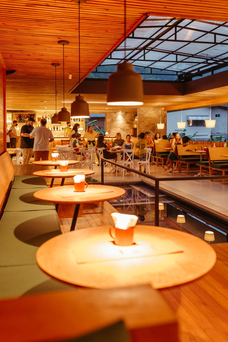 Round candlelit tables in a warm timber-lined restaurant