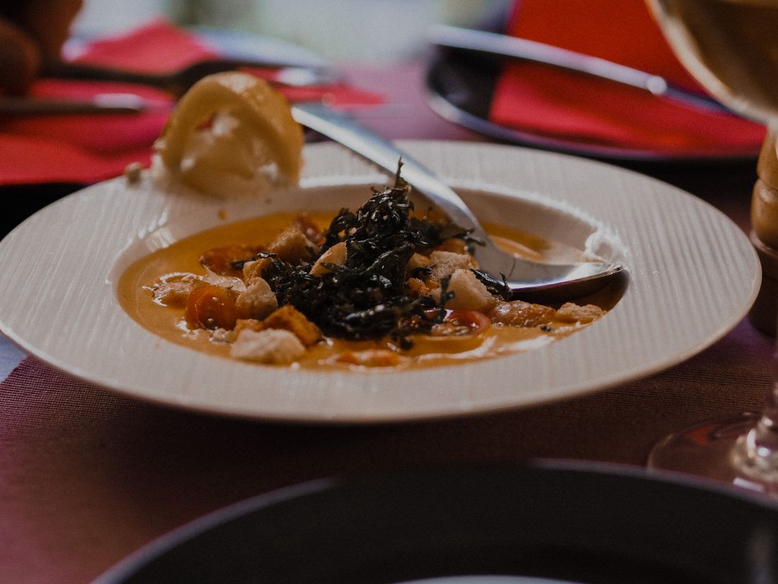 A bowl of saffron seafood broth garnished with sea vegetables