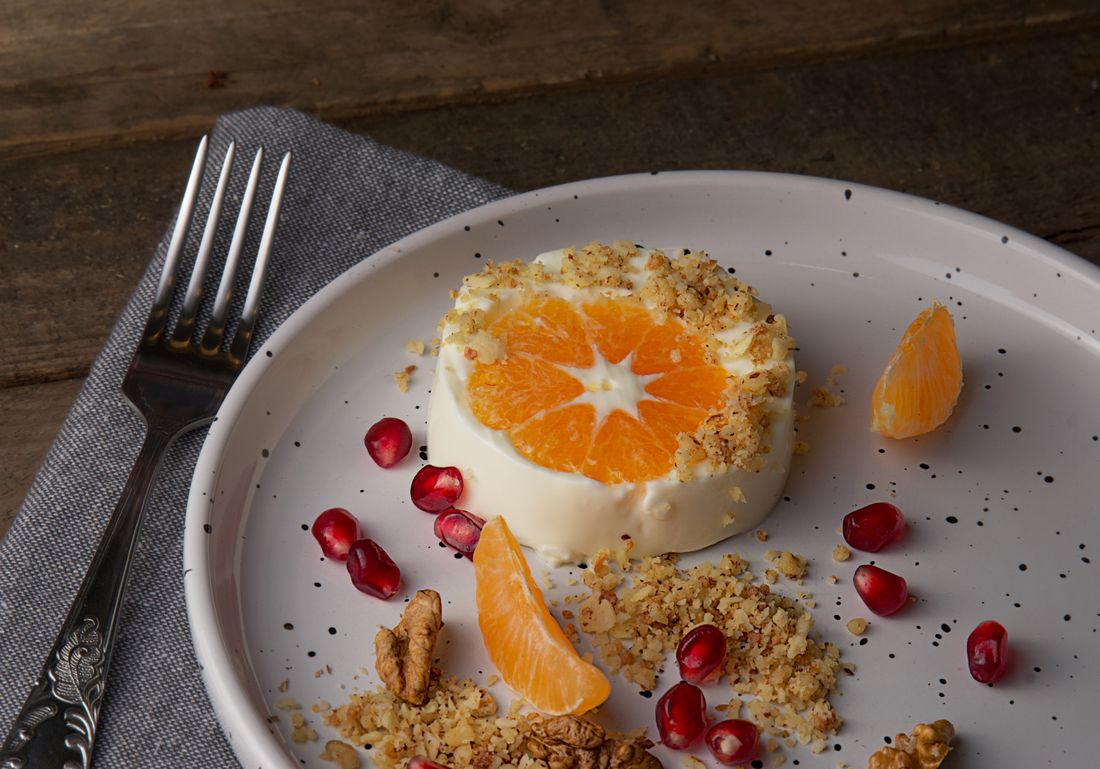 A panna cotta topped with orange segments and pomegranate seeds
