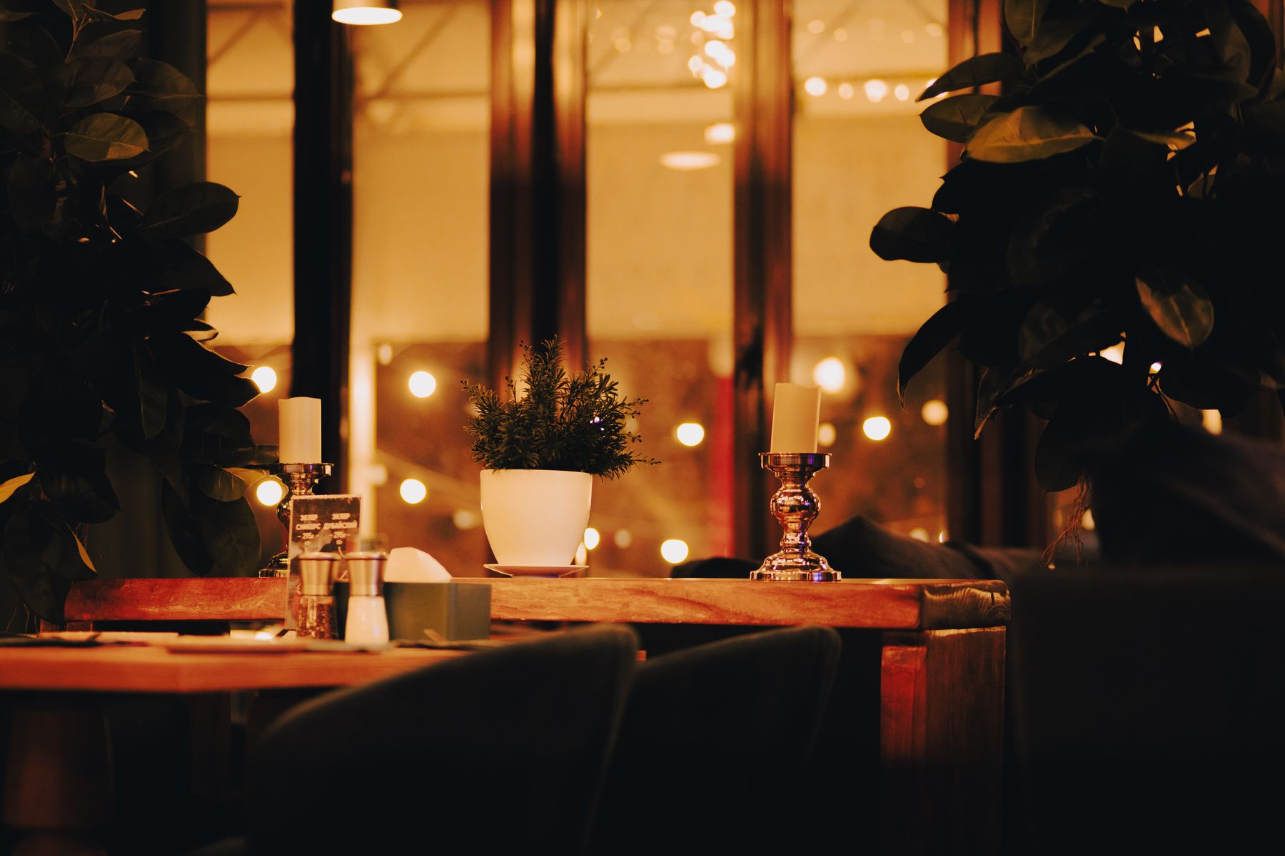 Candlelit restaurant tables with warm pendant lighting and plants