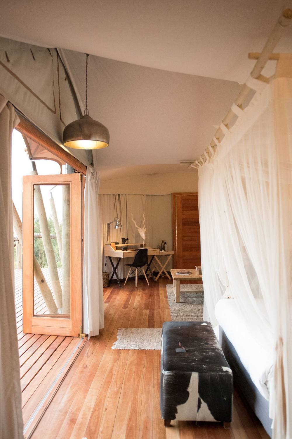 A bench beside white curtains at the doorway of a tent